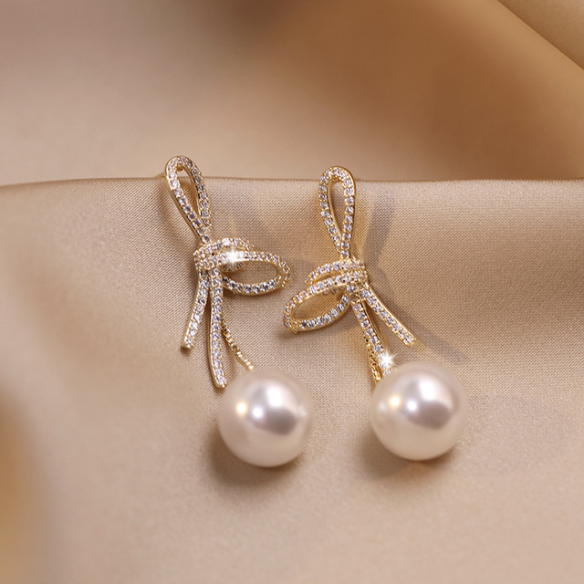 Shining golden pearl earrings with elegant bow